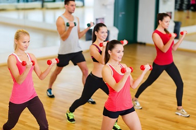 group of smiling people working out with dumbbells